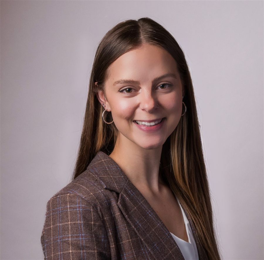 Abigail Peterson smiling, wearing a brown plaid blazer