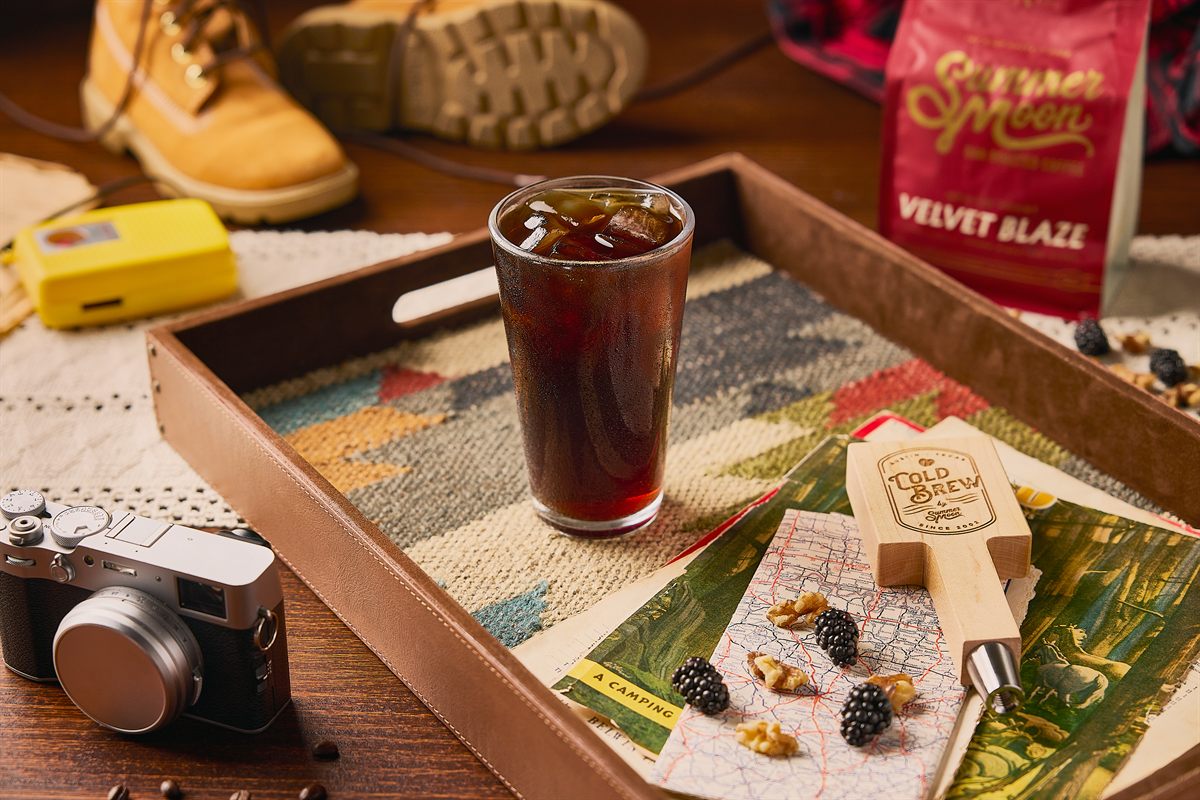 Summer Moon Coffee cold brew on a camping tray with a trail map, blackberries, and a Velvet Blaze coffee bag